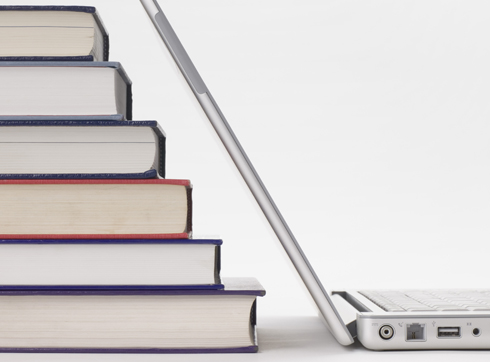 Stack of books with computer next to it