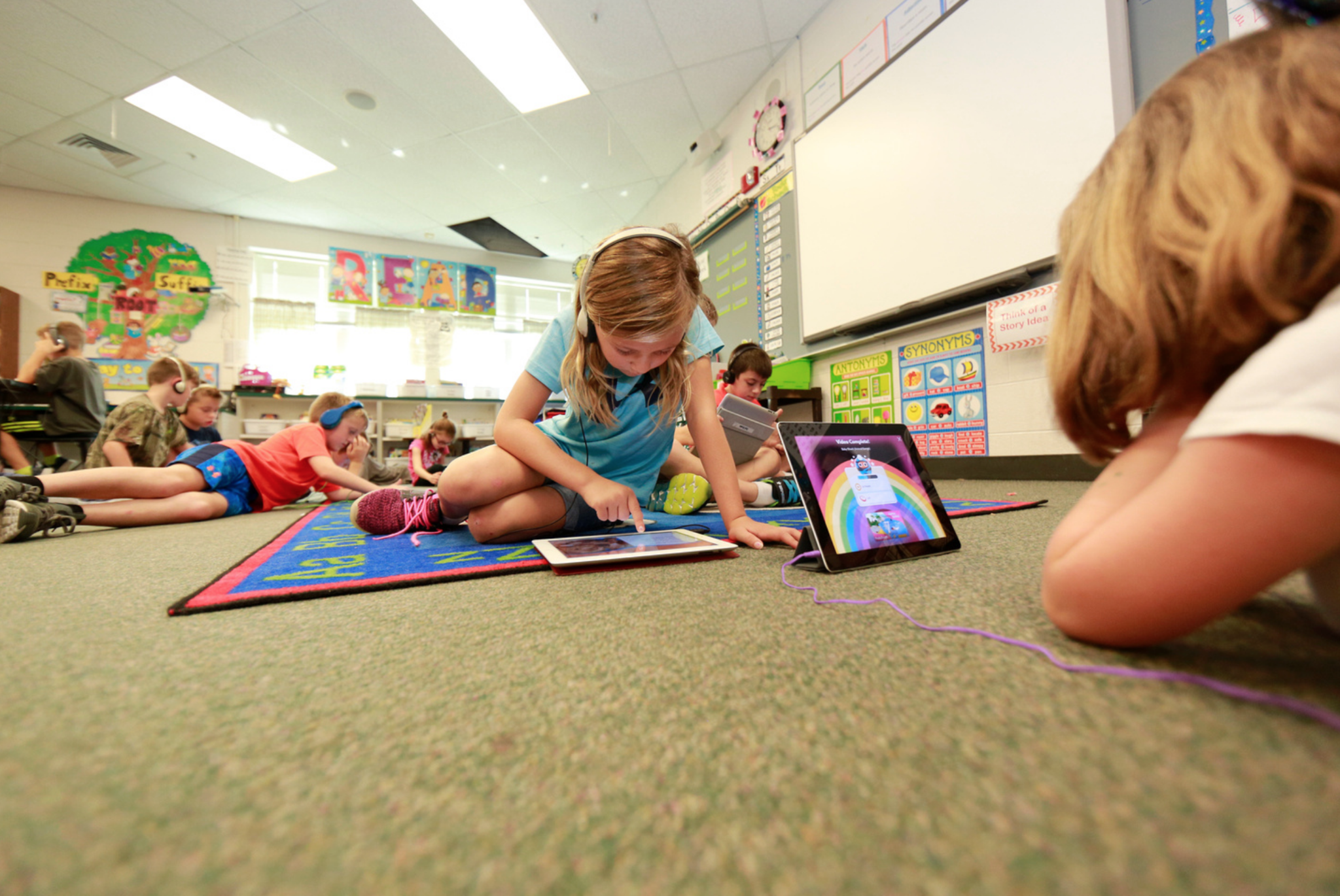 Student on iPad sitting on the floor in classroom